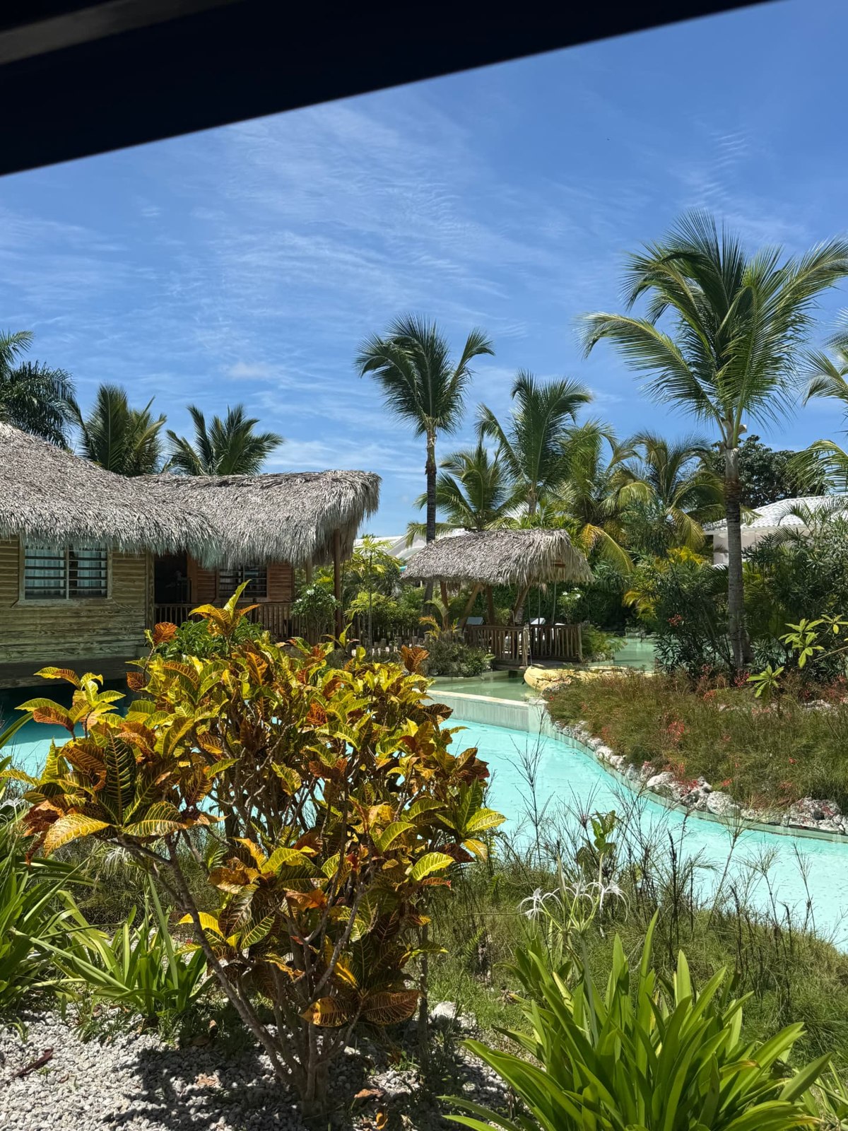 Palm trees, thatched buildings, and turquoise pools at Puntacana Resort