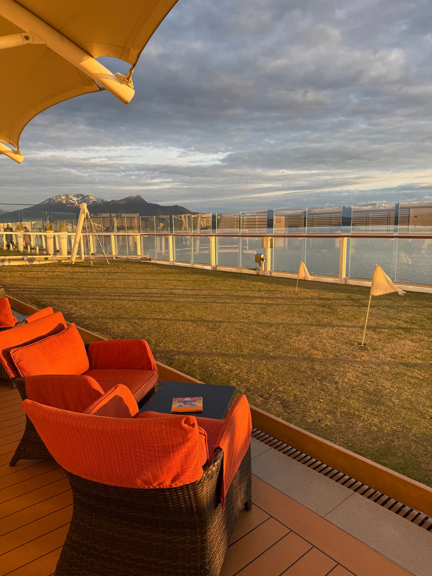 A green lawn with orange lounge chairs and Alaska mountains beyond