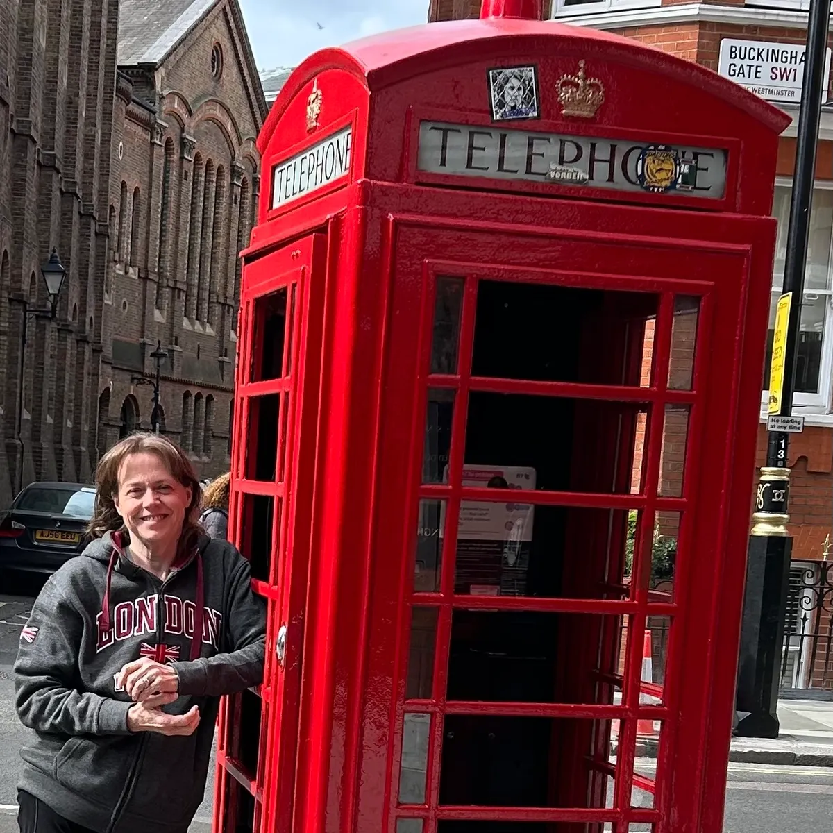 Jennifer Abbott-Walker in a London hoodie beside a red telephone box in London, England.