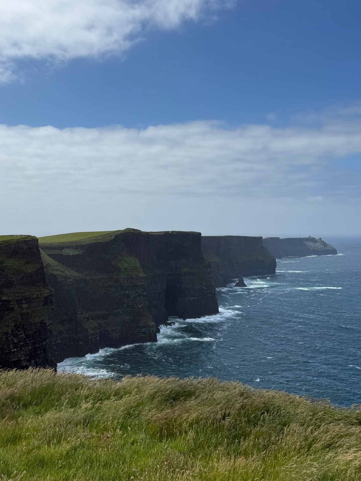 Grass-topped cliffs of Moher rising above the Atlantic beneath a bright sky