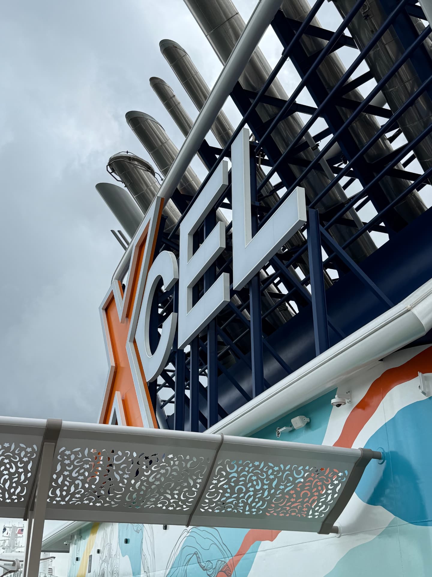 Celebrity Xcel cruise ship funnel and orange X logo against a pale sky