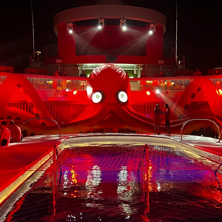The pool deck glowing red during Scarlet Night aboard a Virgin Voyages ship