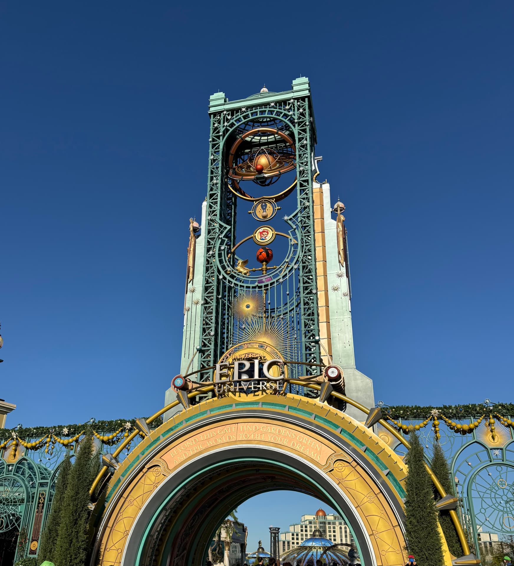 Epic Universe entrance arch with the Chronos tower under a clear blue sky