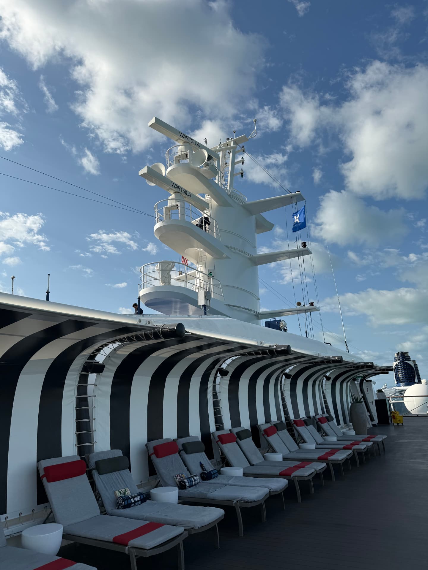 Rows of loungers under black and white striped awnings on the top deck