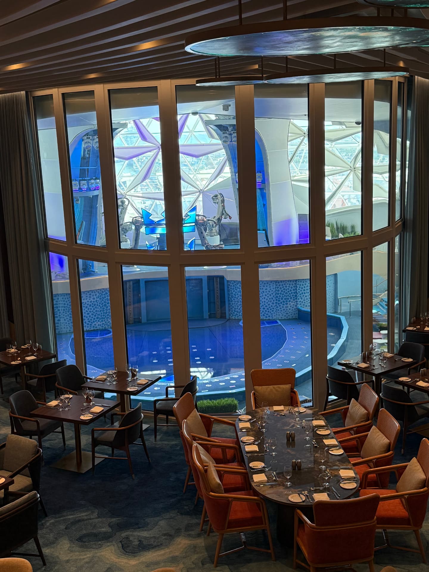A dining room with tall windows overlooking an aqua theater pool