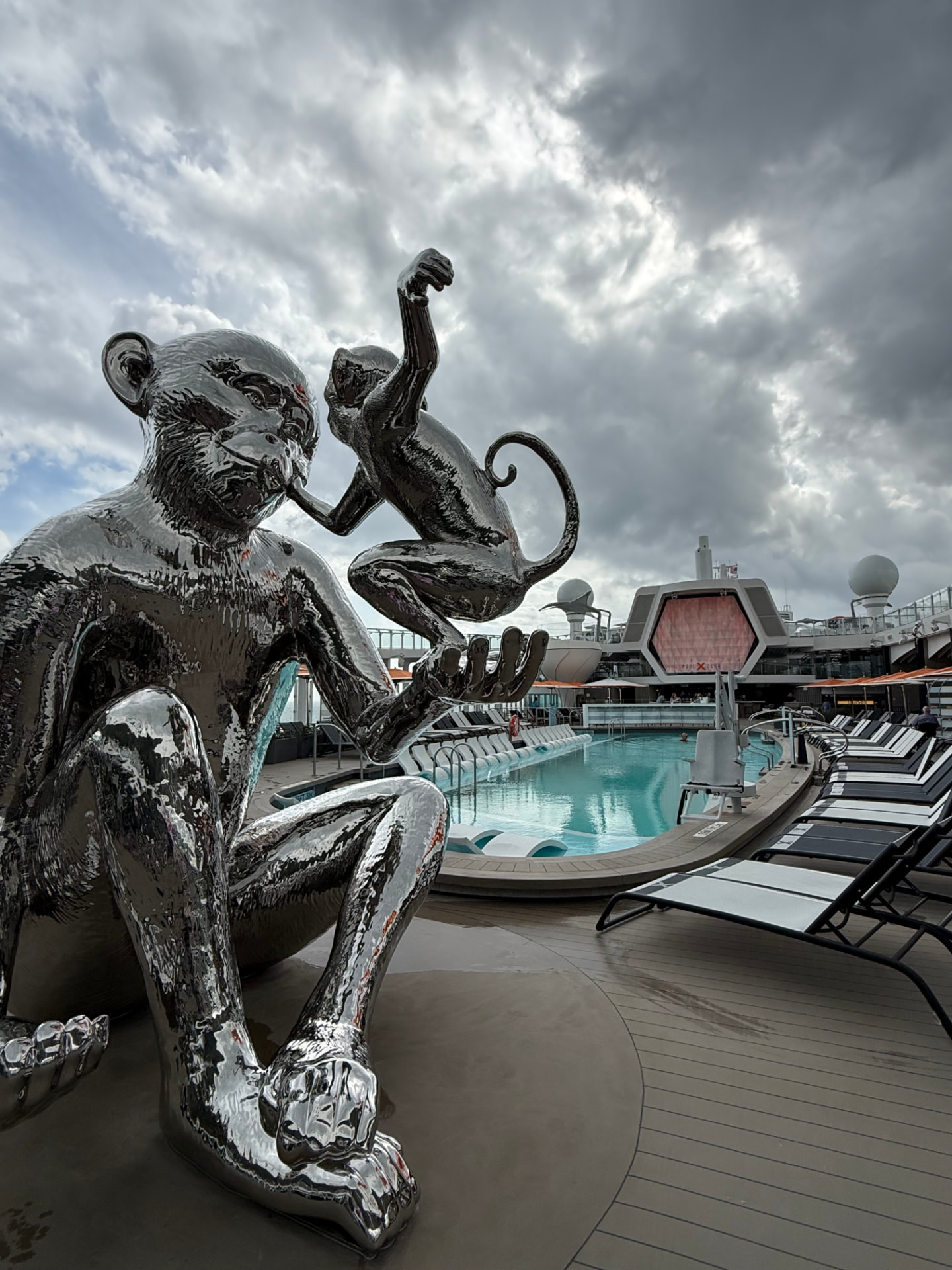 Silver monkey sculptures beside a pool deck
