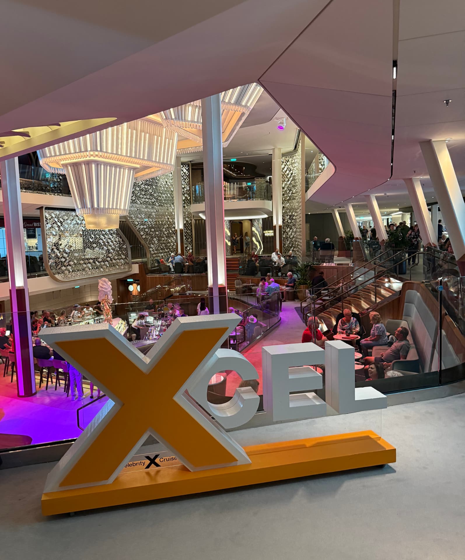 White Xcel letters on an orange base standing in a ship atrium