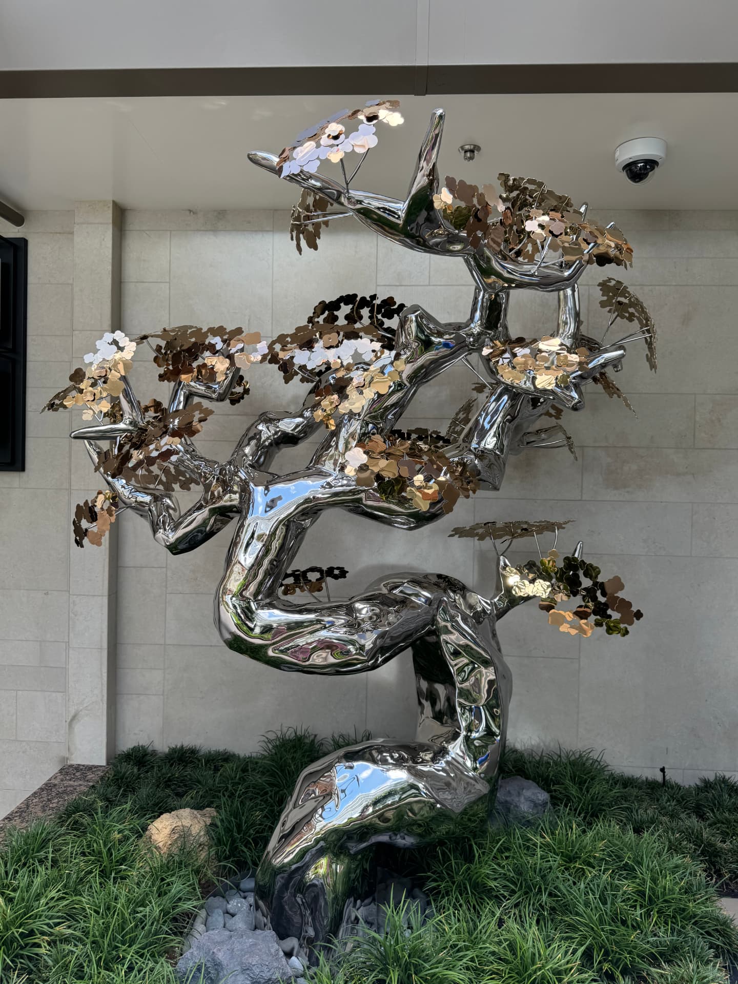 A polished silver tree sculpture with shimmering metallic leaves