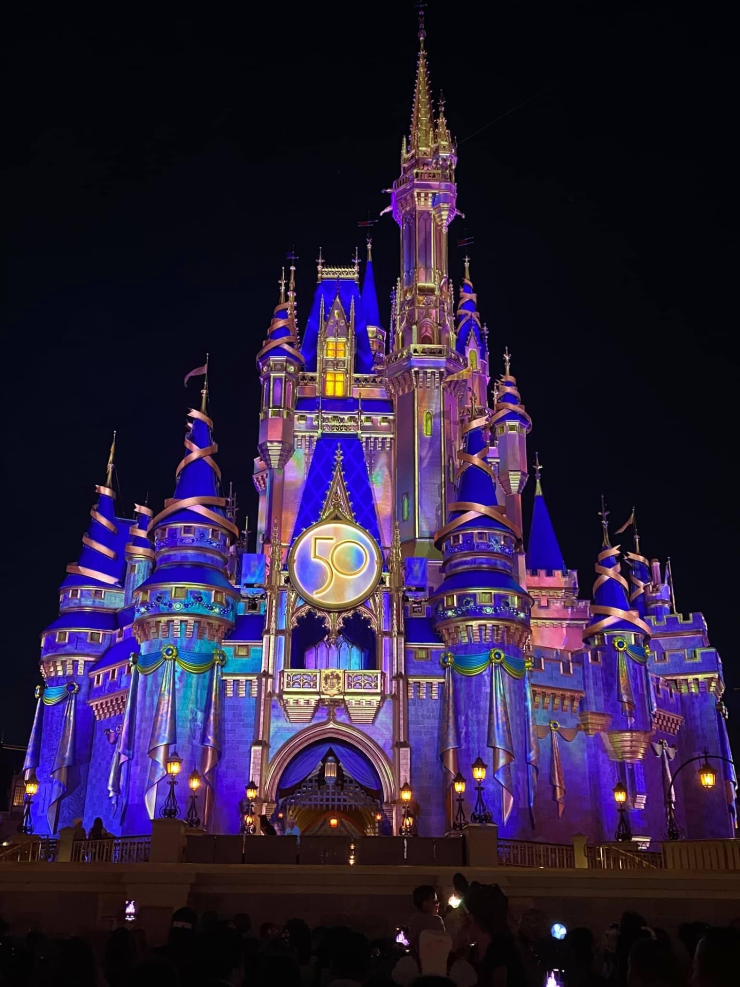 Cinderella Castle glowing in blues and purples after dark at Magic Kingdom