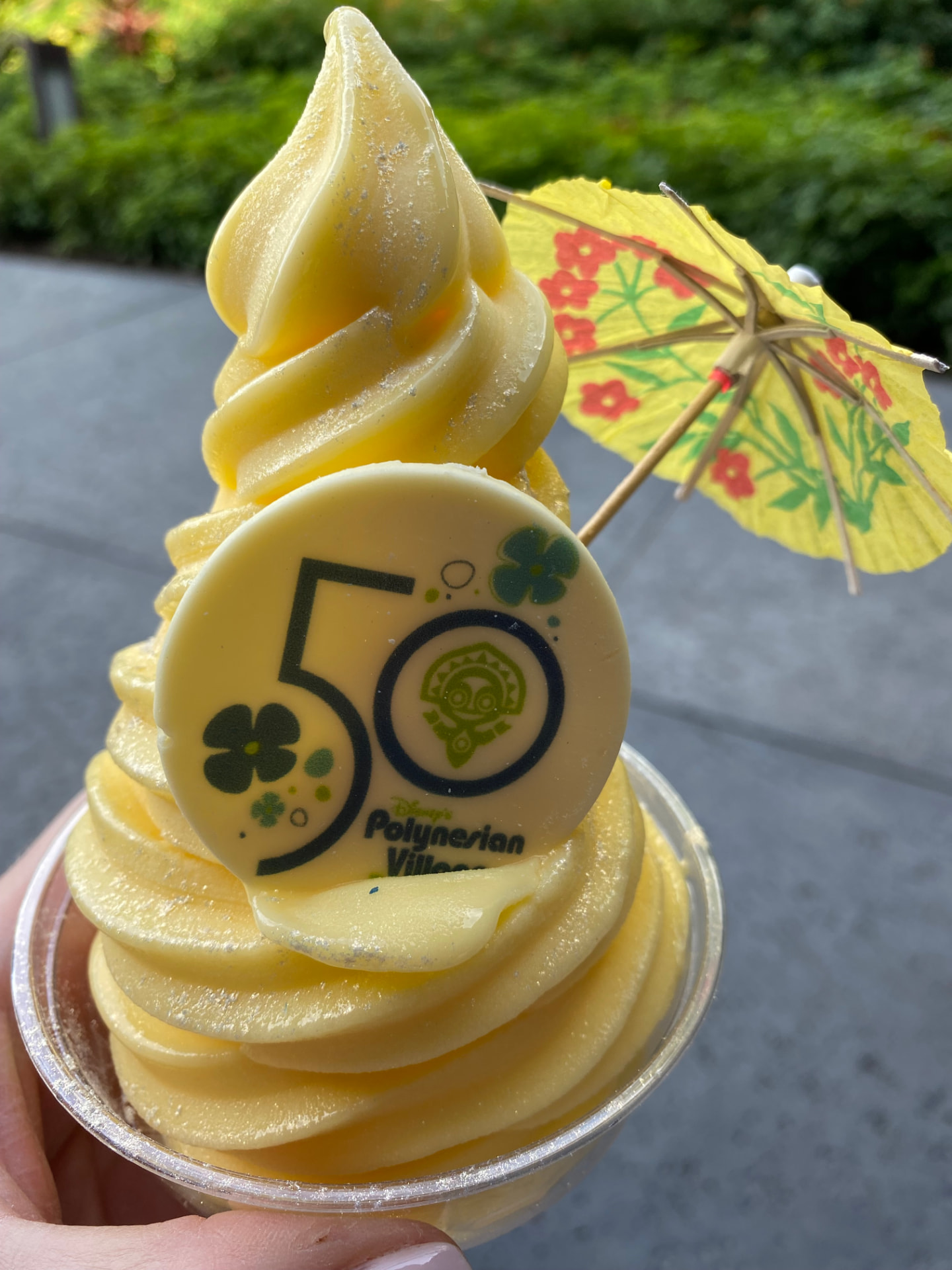 A swirl of Dole Whip topped with an umbrella in a celebration cup